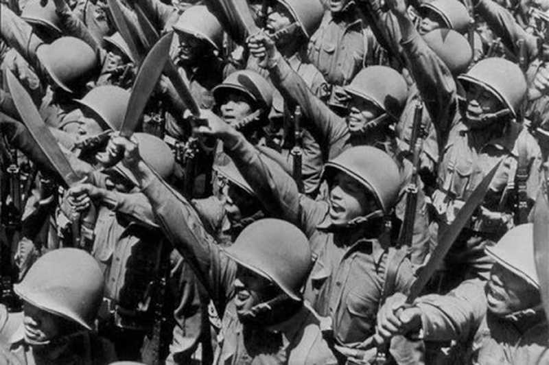 Several Filipino soldiers raise their knives into the air