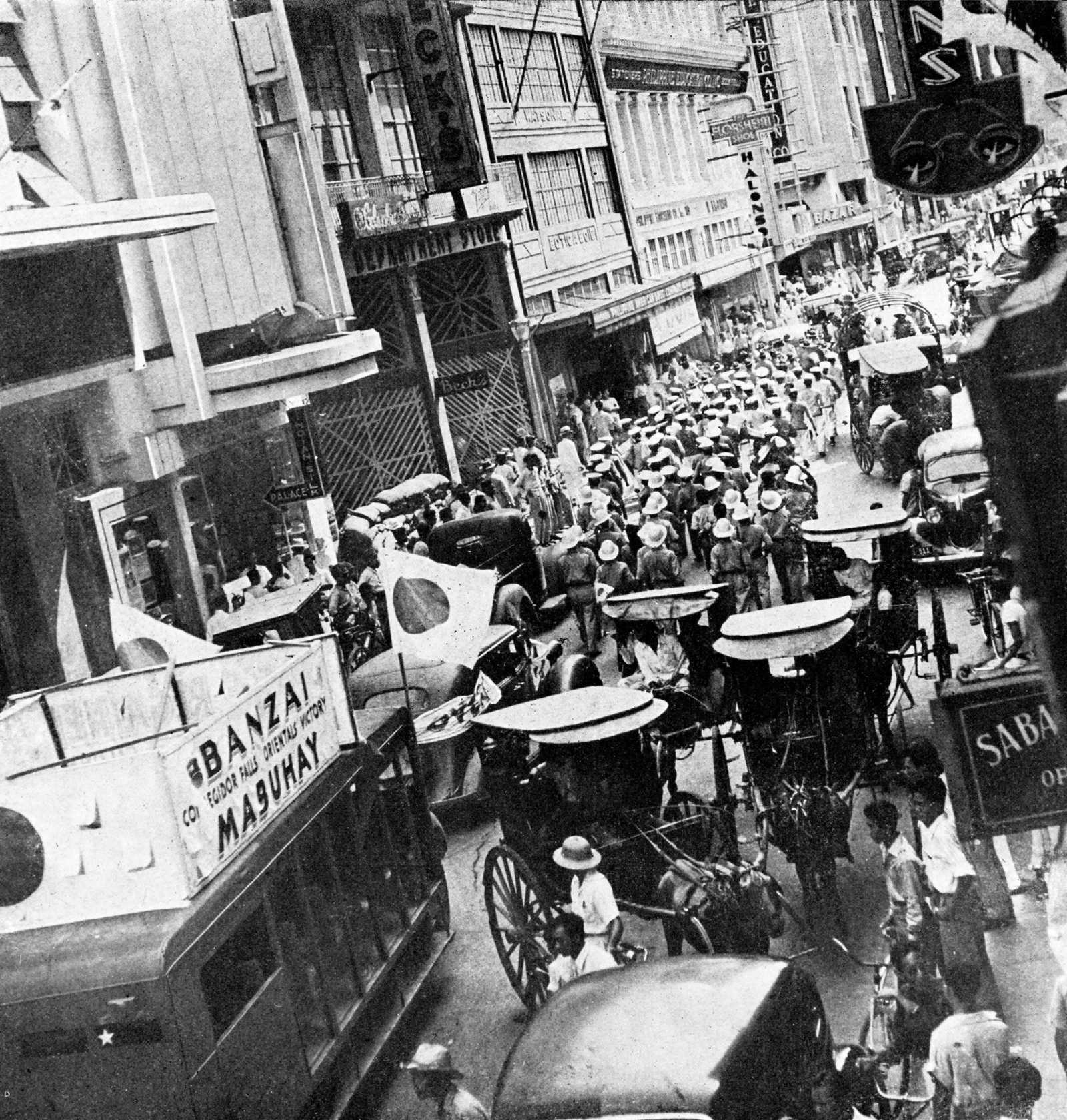 Photo of soldiers marching through town surrounded by Japanese paraphernalia