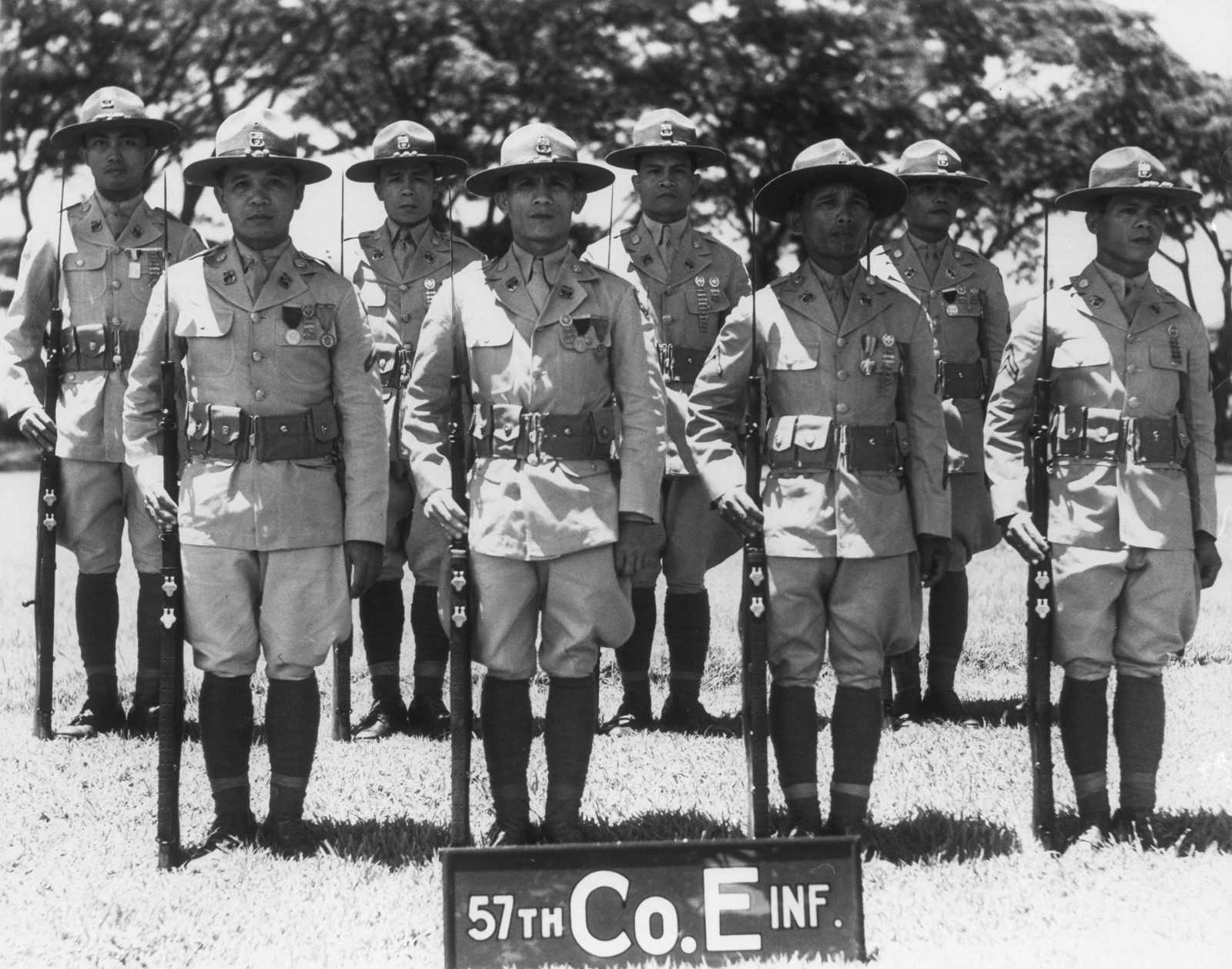 Photo of Philippine Scouts standing in uniform with rifles by their side