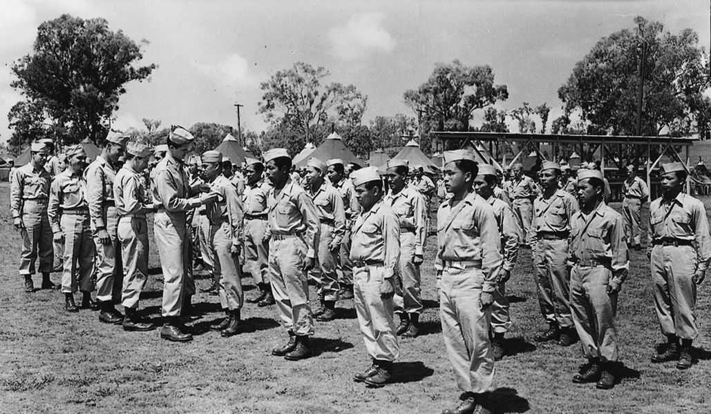 Officers review Filipino soldiers standing in formation, pins a medal onto won soldier