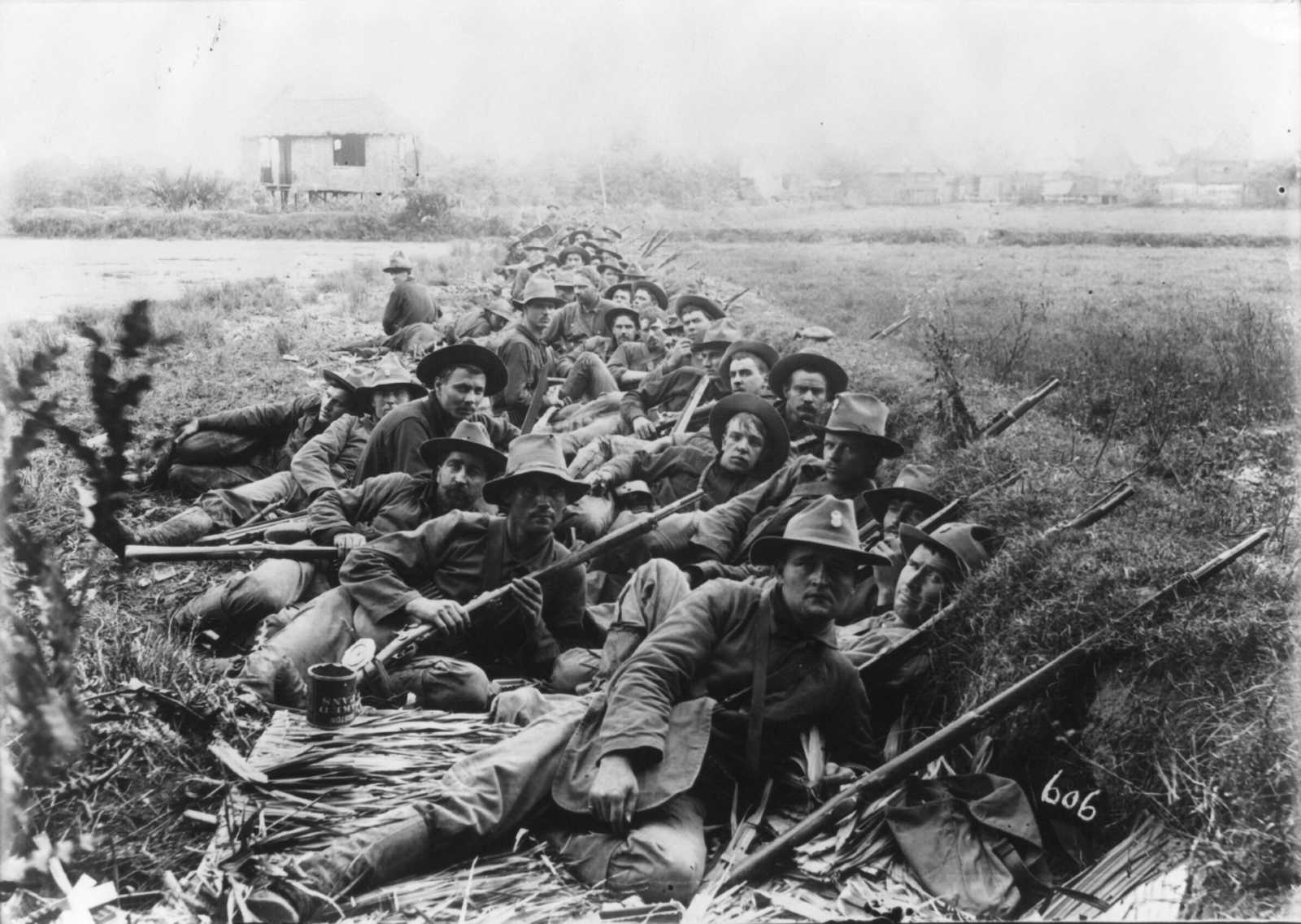 Black and white photo of American soldiers posing in a trench