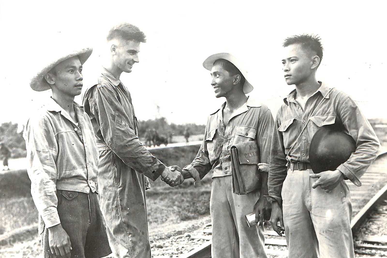 Photo of three Filipinos greeting an American